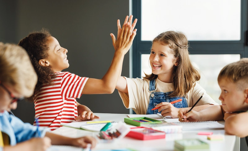 criancas felizes em sala de aula comemorando