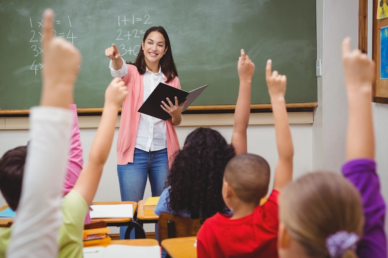 professora apontando para alunos com a mão levantada