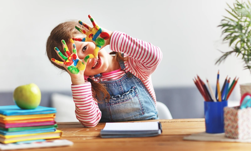 menina com maos sujas de tinta se divertindo