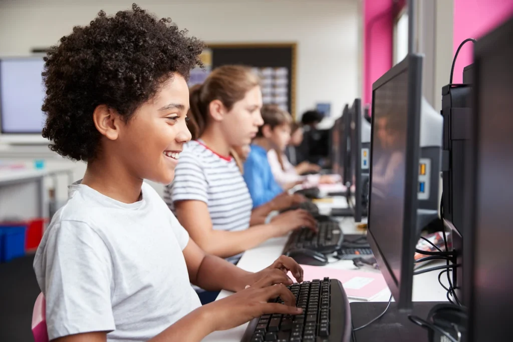 aluno em aula de computacao sorrindo